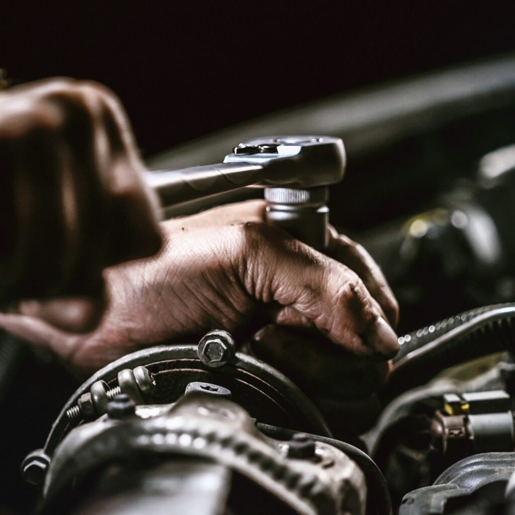 Auto mechanic working on car engine in mechanics garage. Repair service.