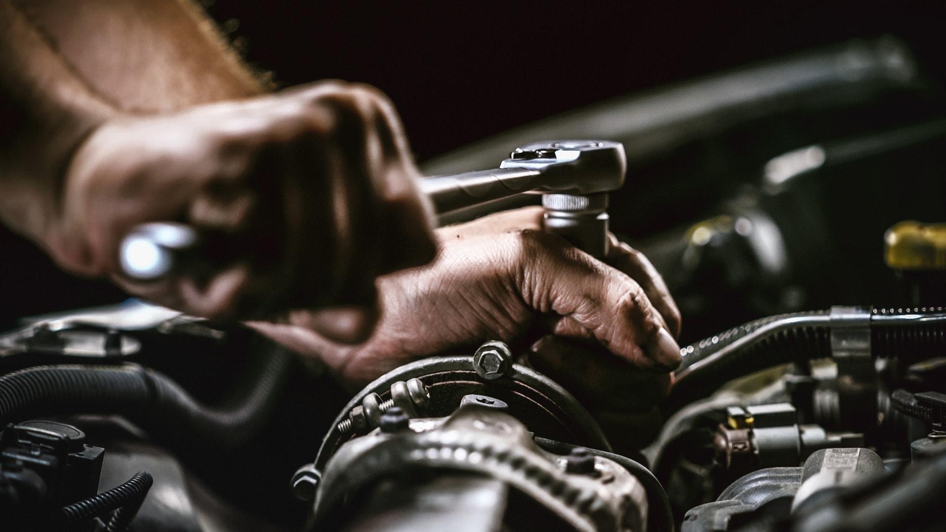 Auto mechanic working on car engine in mechanics garage. Repair service.